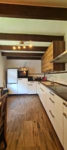 a large kitchen with white cabinets and a wooden floor at Ferienhaus Romy in Hohenfels-Essingen