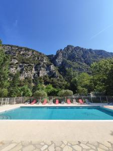 una piscina con sillas y una montaña en el fondo en Le Moulin du Pont D'Aliès, en Axat
