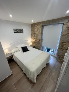 een slaapkamer met een groot bed en een stenen muur bij Casa Xoana in Vilagarcia de Arousa