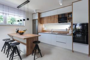 a kitchen with white cabinets and a wooden island with stools at Villa Kaoru brand new Villa with a heated swimming pool in Malinska