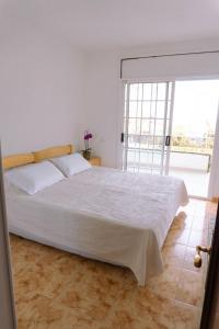 Schlafzimmer mit einem weißen Bett und einem großen Fenster in der Unterkunft Villa Felicidad in Vilanova i la Geltrú