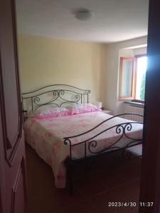 una camera da letto con un letto con una coperta rosa e una finestra di Popetto casa vacanza a Tresana