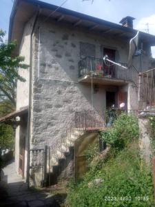 un edificio in pietra con scala e balcone di Popetto casa vacanza a Tresana