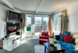ein Wohnzimmer mit einem blauen Sofa und einem Kamin in der Unterkunft Tremblant Mountain Resort Condo! in Mont-Tremblant