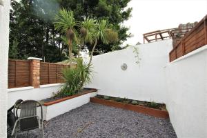 a chair sitting next to a white wall with palm trees at Lovely 2BR home with sunny garden in Montpelier in Bristol