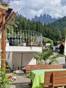 a balcony with a table and benches and mountains at Appartements Pension Sonia in Funes