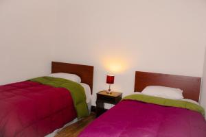 two beds in a room with pink and green sheets at Nishihouse in Cusco