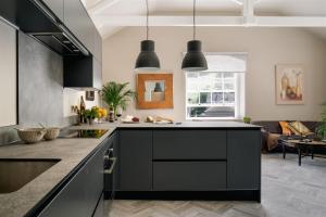 a kitchen with black cabinets and a living room at The Upper School House in Ashburton