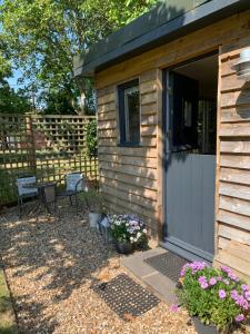 une petite maison avec une porte grise et quelques fleurs dans l'établissement Little Banks Cabin, à Ringwood