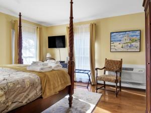 a bedroom with a bed and a chair and a television at The Thistle Inn in Boothbay Harbor