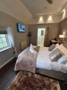 a bedroom with a large bed and a tv on the wall at Old Thatch Bambers Green in Takeley