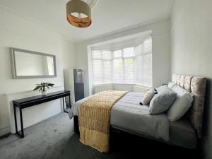 a bedroom with a bed and a table and a window at Perfect Location Whole Apartment With Wifi & Private Garden CONTRACTORS WELCOME in Southend-on-Sea