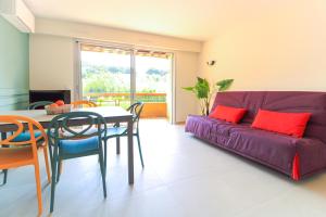 ein Wohnzimmer mit einem lila Sofa, einem Tisch und Stühlen in der Unterkunft SELECT'soHOME - Charmant T2 proche de la plage de Saint-Clair au Lavandou avec parking privé - PARCFO11 in Le Lavandou