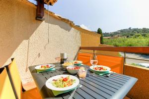 een tafel met borden en glazen wijn bij SELECT'soHOME - Charmant T2 proche de la plage de Saint-Clair au Lavandou avec parking privé - PARCFO11 in Le Lavandou