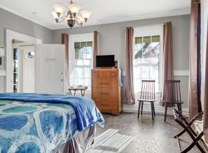 a bedroom with a bed and a dresser and windows at The Thistle Inn in Boothbay Harbor