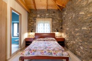 Eftichia's Nomad stone house : غرفة نوم بسرير وجدار حجري
