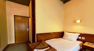 um pequeno quarto com uma cama e uma porta em Hotel Sax Balkan em Dimitrovgrad