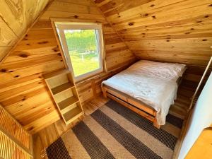 a bedroom in a log cabin with a bed and a window at Domki na Mazurach - Marksewo in Szczytno