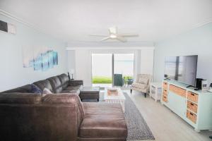een woonkamer met een bank en een plafondventilator bij Colony Beach Club 101 in New Smyrna Beach