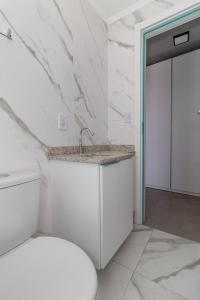La salle de bains blanche est pourvue d'un lavabo et de toilettes. dans l'établissement Studio Residencial no coração do 4° Distrito, à Porto Alegre