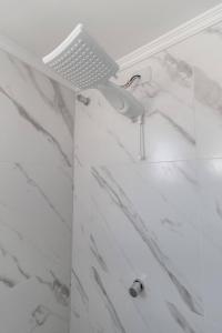 La salle de bains est pourvue d'une douche et de murs en marbre blanc. dans l'établissement Studio Residencial no coração do 4° Distrito, à Porto Alegre