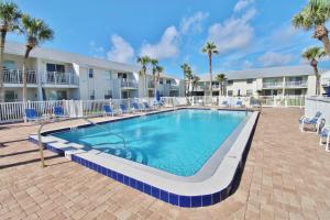 een zwembad op een binnenplaats met stoelen en palmbomen bij Colony Beach Club 101 in New Smyrna Beach