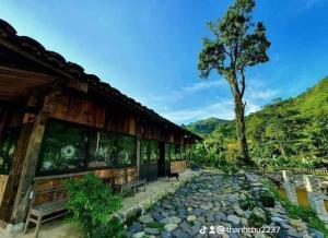 a building with a bench in front of a tree at Lũng Mười Homestay in Nà Giảo