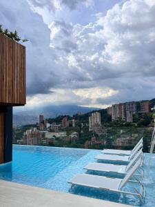 um grupo de espreguiçadeiras à beira de uma piscina em Binn Hotel em Medellín