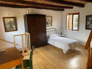 een slaapkamer met een bed en een houten vloer bij Tipico rustico in pietra friulana in Budoia