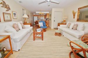 ein Wohnzimmer mit 2 weißen Sofas und einem Tisch in der Unterkunft Colony Beach Club 128 in New Smyrna Beach
