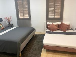 a bedroom with two beds and two windows at Barcelona Chic Apartments- Free Parking-10 min by metro from BCN Center in Barcelona