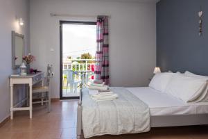 a bedroom with a bed and a desk and a balcony at Theodora Studios in Argassi