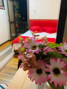Residenciais Maria Flor في غرامادو: مزهرية مع الزهور الزهرية على طاولة في غرفة النوم