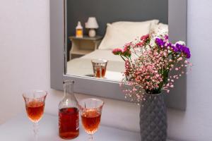 a vase of flowers and a bottle of wine and two glasses at Theodora Studios in Argassi +36 photos