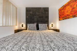 een slaapkamer met een groot bed en een schilderij aan de muur bij Unik Heliopolis naturiste in Cap d'Agde