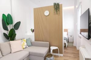 ein Wohnzimmer mit einem Sofa und einer Uhr an der Wand in der Unterkunft Acogedor y conveniente piso reformado en Salamanca in Madrid