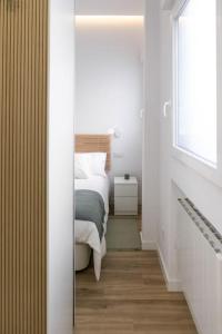 1 dormitorio con cama, ventana y espejo en Acogedor y conveniente piso reformado en Salamanca, en Madrid