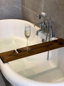 a glass of wine sitting on a wooden shelf in a bath tub at Dovecote Cottage. in Newcastle upon Tyne