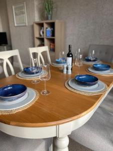 a wooden table with plates and wine glasses on it at Dovecote Cottage. in Newcastle upon Tyne