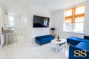 uma sala de estar com sofás azuis e uma televisão em Blue Lagoon - 1 MINUTE FROM 02 ACADEMY - FREE PARKING - 5 MINUTES FROM THE BEACH - FAST WI-FI - SMART TV em Bournemouth