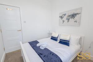 een witte slaapkamer met een bed met blauwe en witte kussens bij Blue Lagoon - 1 MINUTE FROM 02 ACADEMY - FREE PARKING - 5 MINUTES FROM THE BEACH - FAST WI-FI - SMART TV in Bournemouth