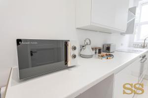 una cocina blanca con microondas en una encimera en Blue Lagoon - 1 MINUTE FROM 02 ACADEMY - FREE PARKING - 5 MINUTES FROM THE BEACH - FAST WI-FI - SMART TV en Bournemouth