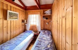 twee bedden in een kamer met houten wanden en een raam bij Pet Friendly Home In Fvang With Kitchen in Tromsnes
