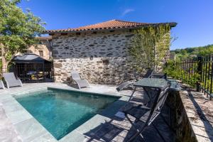 a pool with chairs and a table in front of a house at Newly renovated fort with panoramic landscape view jacuzzi & billiard in Leynhac