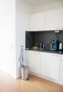 a kitchen with white cabinets and a trash can at Gastenverblijf Janssen in Schagen (NH) in Schagen