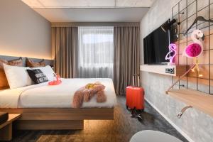 ein Hotelzimmer mit einem Bett und einem TV in der Unterkunft Moxy Sion in Sion