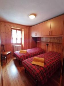 two beds in a room with wooden floors and cabinets at Appartamento sul Liro in Campodolcino