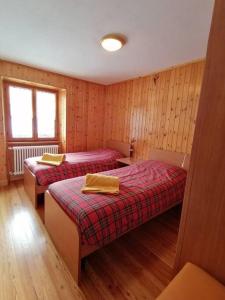 two beds in a room with wooden walls at Appartamento sul Liro in Campodolcino