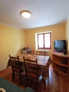 a room with a table and chairs and a television at Appartamento sul Liro in Campodolcino