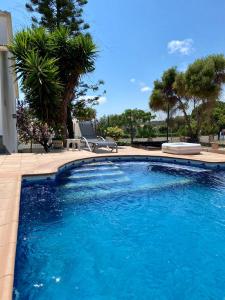 een zwembad met blauw water in een tuin bij Villa Felicidad in Vilanova i la Geltrú